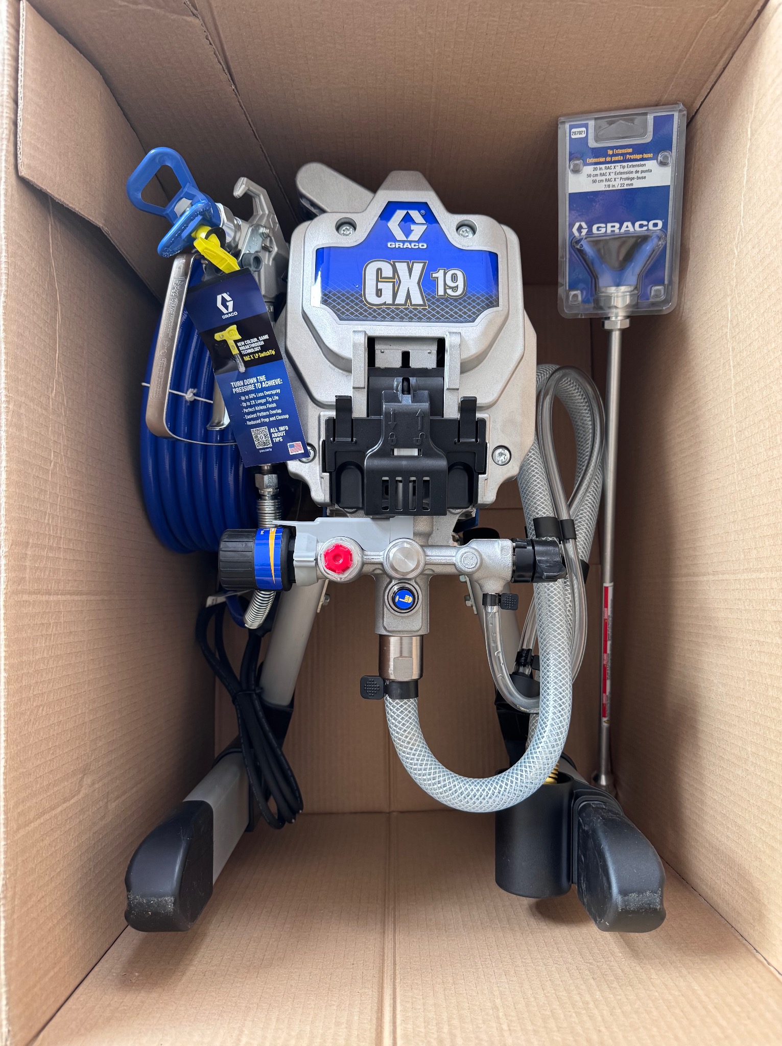 Nowy, nierozpakowany agregat malarski Graco GX19 w kartonowym pudełku, z akcesoriami i instrukcją. Sprzęt gotowy do użycia w pracach malarskich.