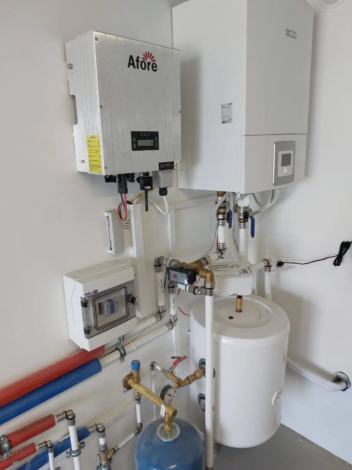 Instalacja z inwerterem Afore, kotłem Bosch oraz zbiornikiem buforowym w pomieszczeniu technicznym, widoczne liczne rury i zawory.