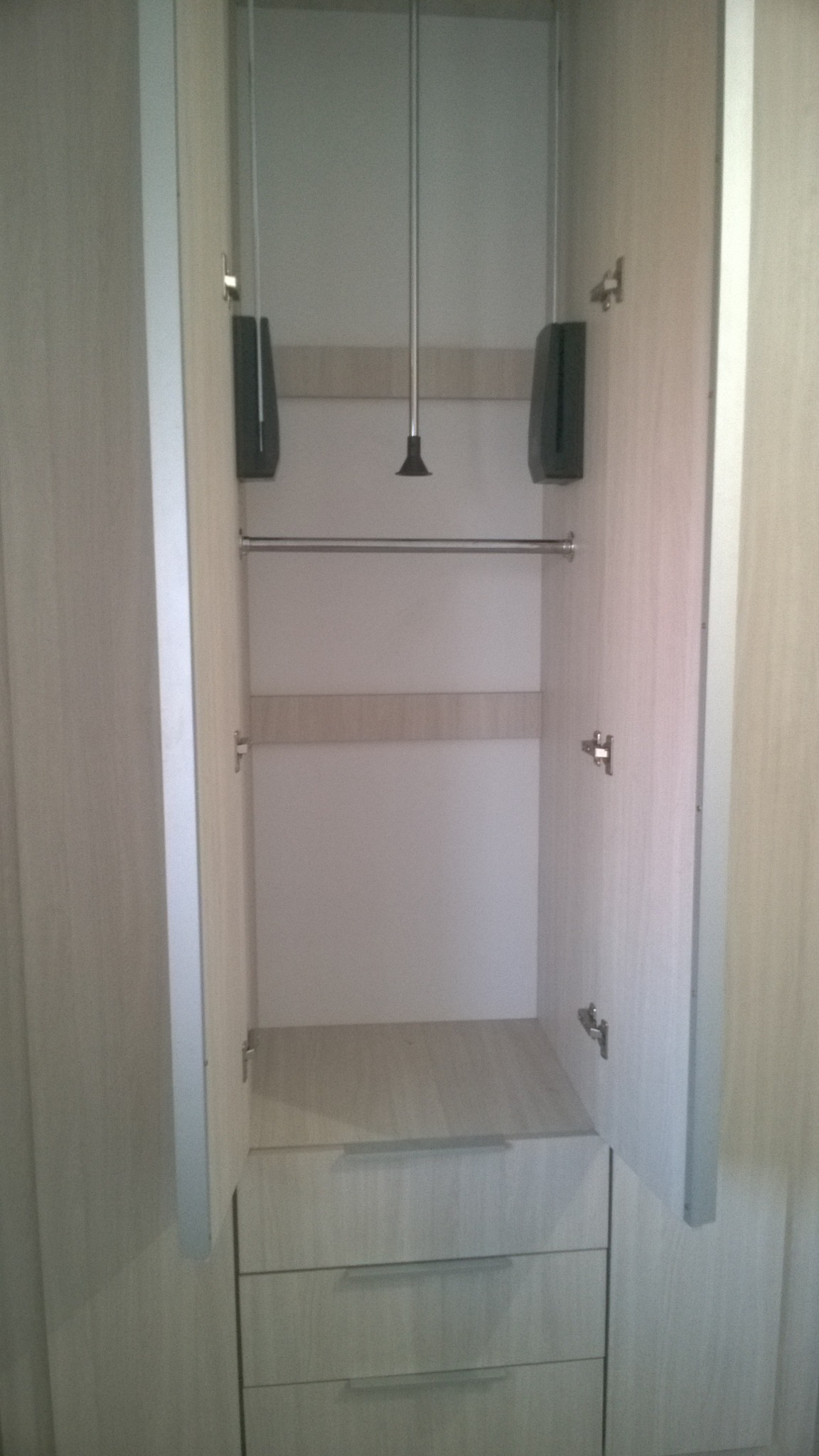 Wnętrze szafy z szufladami i drążkiem na ubrania, system podnoszenia drążka widoczny, wykonana w Jerzykowo.