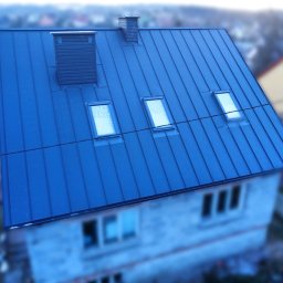 Firma Dekarska - Niebieski dach z blachy na domu z trzema oknami dachowymi i dwoma kominami, widziany z góry pod kątem.