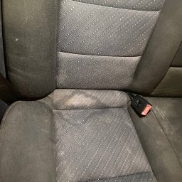 CleanAuto WaWa - Zabrudzone siedzisko fotela samochodowego z pasami bezpieczeństwa, wymagające czyszczenia, widoczne plamy na tapicerce w Warszawie.