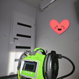 Klim-Tech Paweł Klimkiewicz - Myjka do klimatyzacji marki WIPCOOL z wyświetlaczem, w tle biały klimatyzator na ścianie i drzwi z czarnymi paskami, u góry naklejka w kształcie serca.