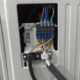 Podłączenie przewodów elektrycznych do listwy zaciskowej wewnątrz obudowy klimatyzatora; widoczne oznaczenia L, LO, N, S oraz uziemienie.