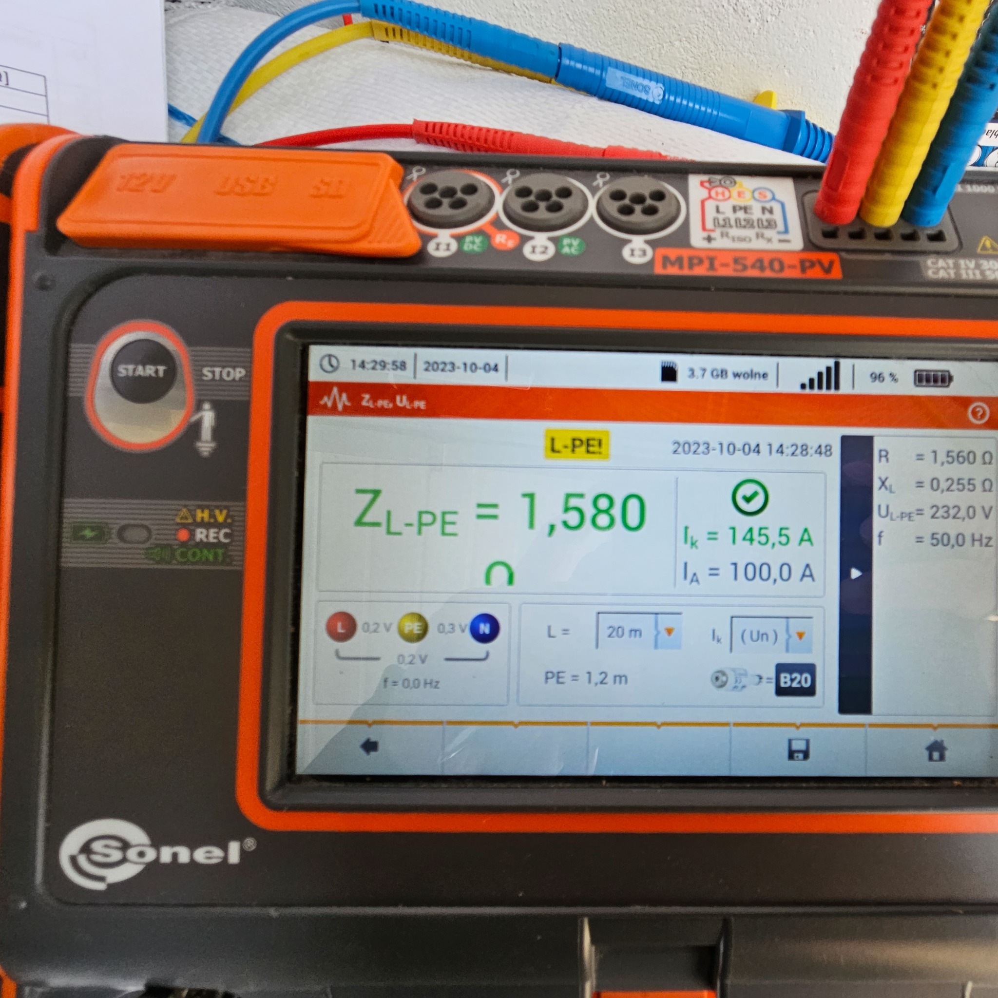 Miernik elektryczny Sonel MPI-540-PV z kolorowymi przewodami pomiarowymi, wyświetlający wynik pomiaru impedancji pętli zwarcia ZL-PE na poziomie 1,580 Ω oraz prądy Ik i Ia, data i godzina pomiaru...