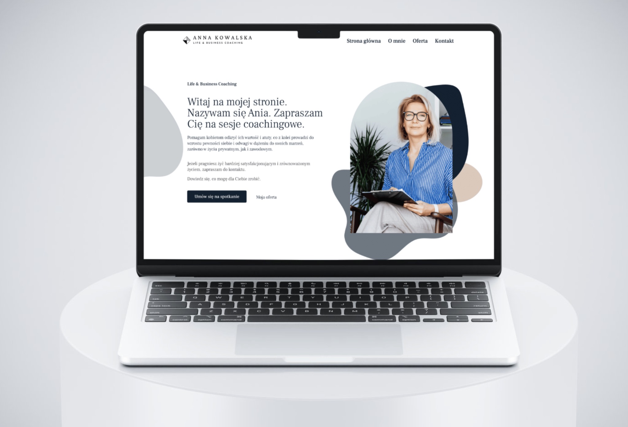 Laptop wyświetlający stronę internetową z wizerunkiem kobiety-coach i tekstem zapraszającym na sesje coachingowe, na białym tle.