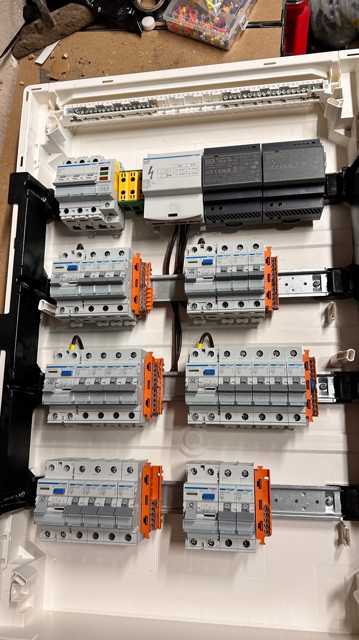 Rozdzielnica elektryczna z zamontowanymi bezpiecznikami Hager, widoczne kable i listwa zaciskowa, skrzynka częściowo wypełniona, widok z góry.