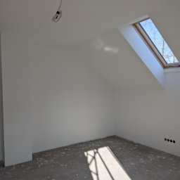 Luxs-Montaż-Bud - Poddasze w Warszawie po wyrównaniu ścian gładzią, widoczne okno dachowe i przygotowane gniazdka elektryczne.