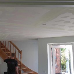 RDK. Serwis - Przygotowanie sufitu do malowania: widoczne ślady po szpachlowaniu w pomieszczeniu z drewnianymi schodami i białymi drzwiami balkonowymi.