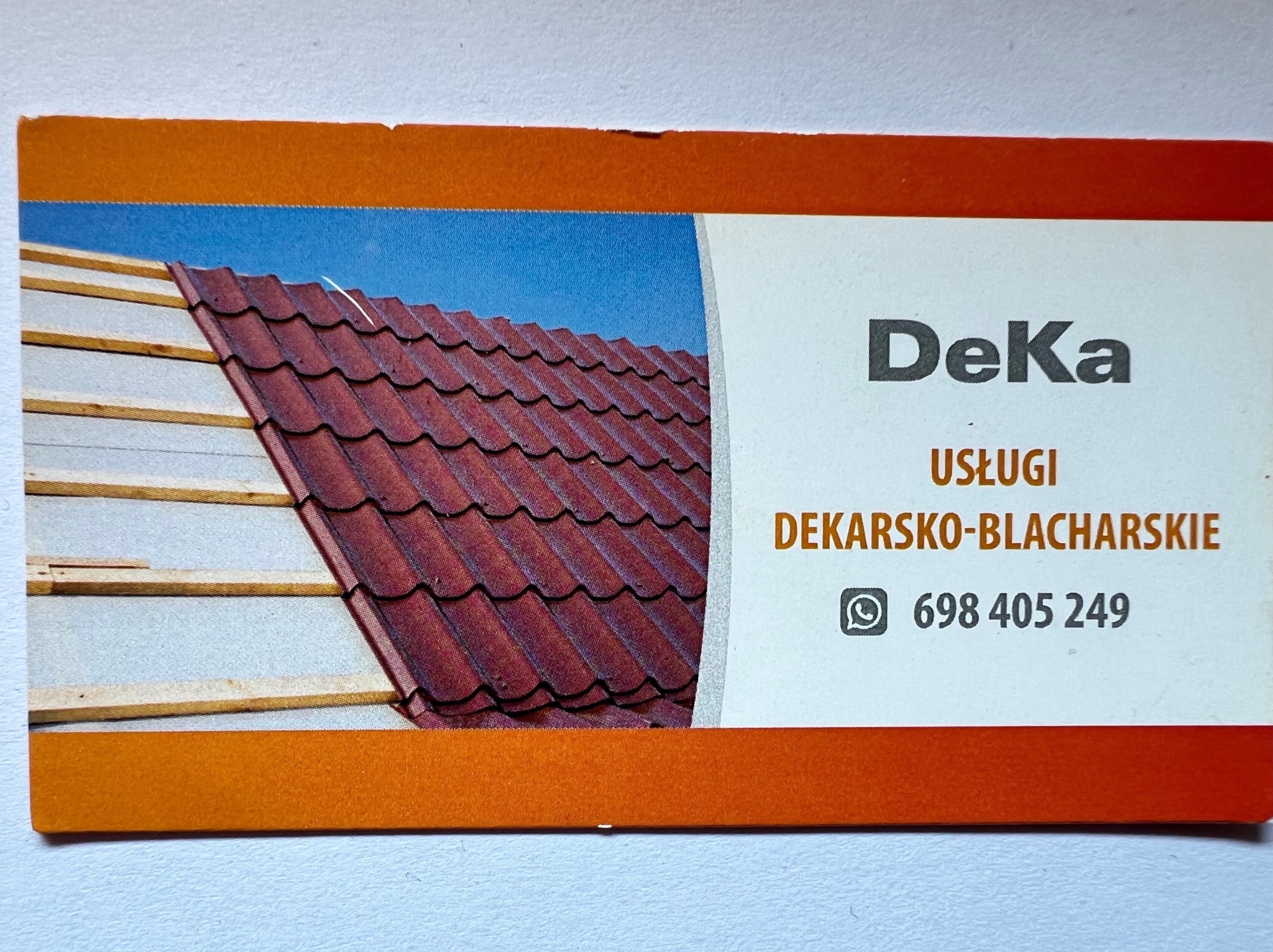 Wizytówka firmy dekarsko-blacharskiej DeKa z Jarocina prezentująca fragment dachu w trakcie budowy, z widoczną konstrukcją drewnianą i częściowo ułożoną czerwoną dachówką.