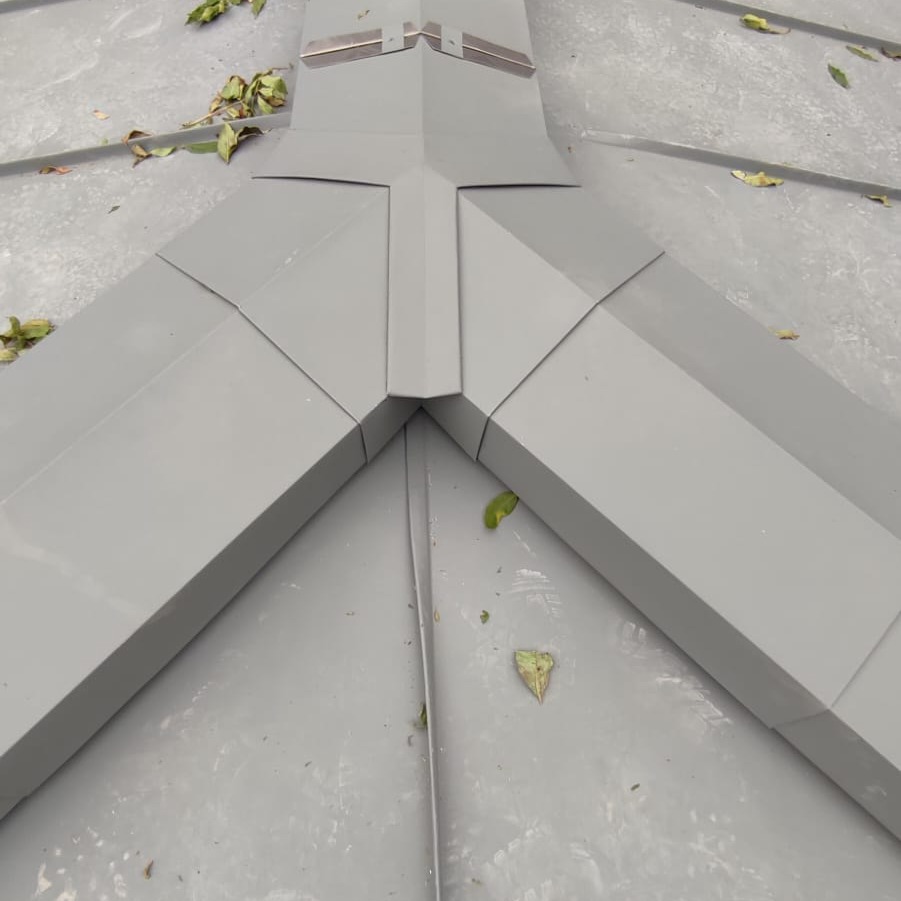 Szare, metalowe obróbki blacharskie na dachu, widok z góry, z liśćmi na powierzchni.