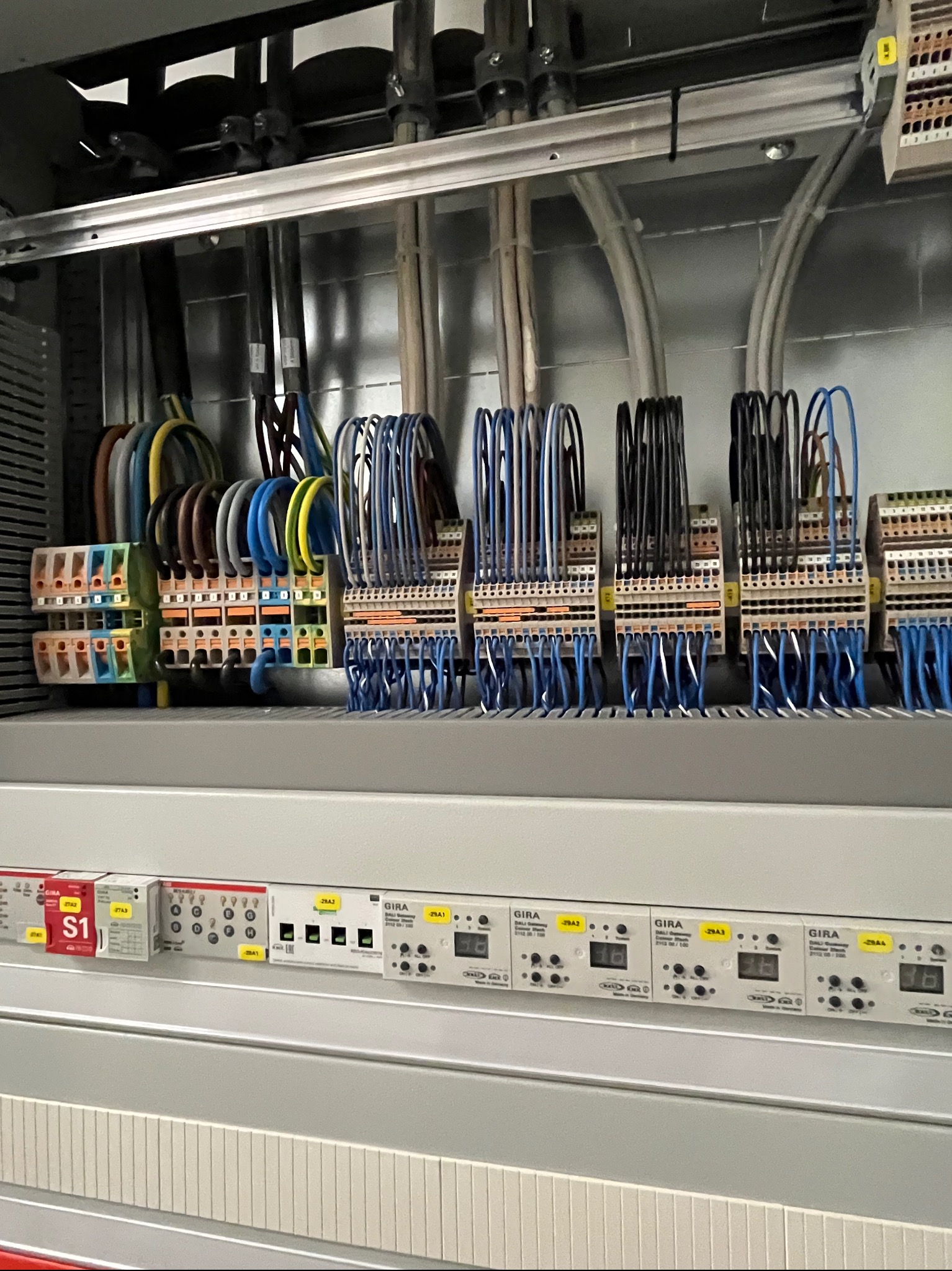 Szafa sterownicza z widocznymi przewodami, złączkami i modułami GIRA. Precyzyjne połączenia elektryczne w szarej obudowie.