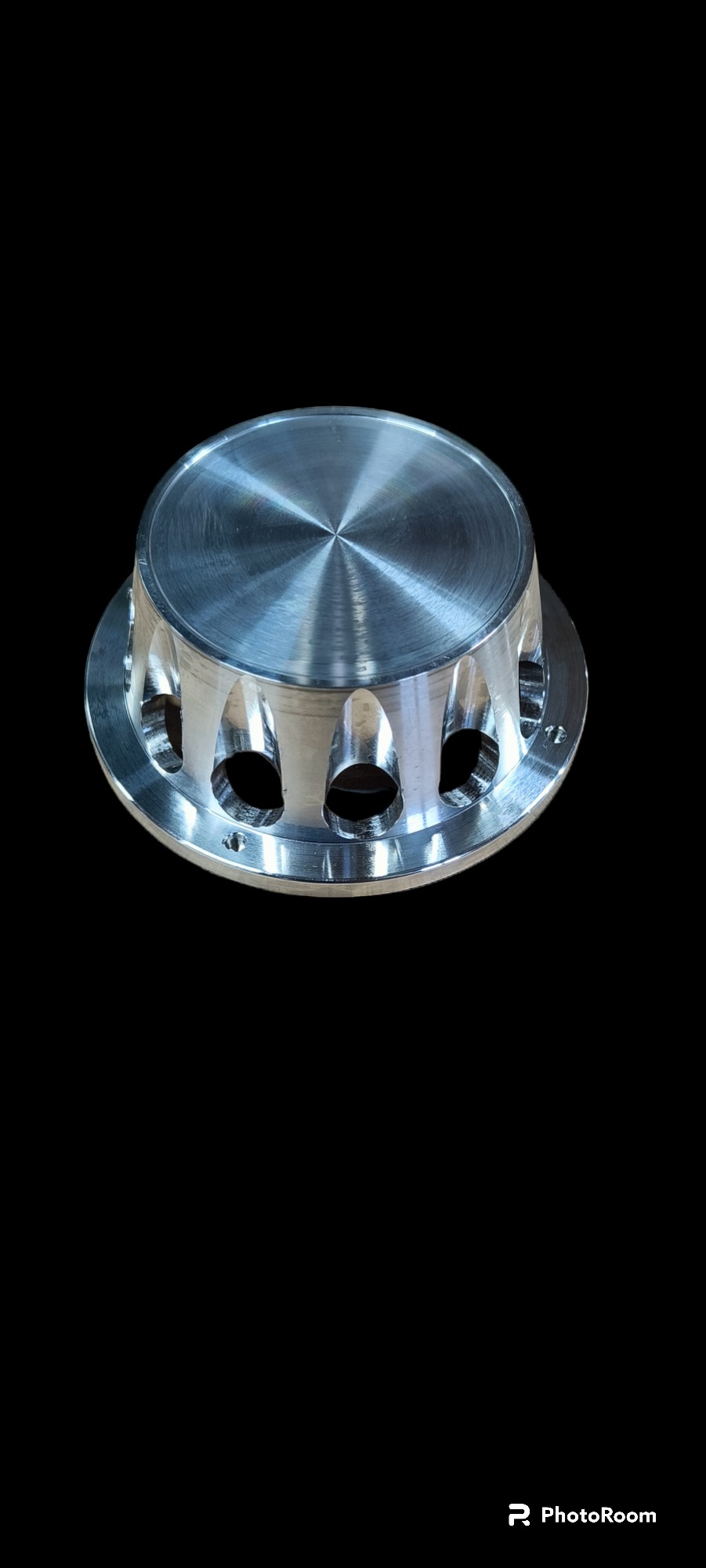 Precyzyjnie wykonany, metalowy element z otworami, obrobiony na tokarce CNC, widoczne ślady obróbki skrawaniem.