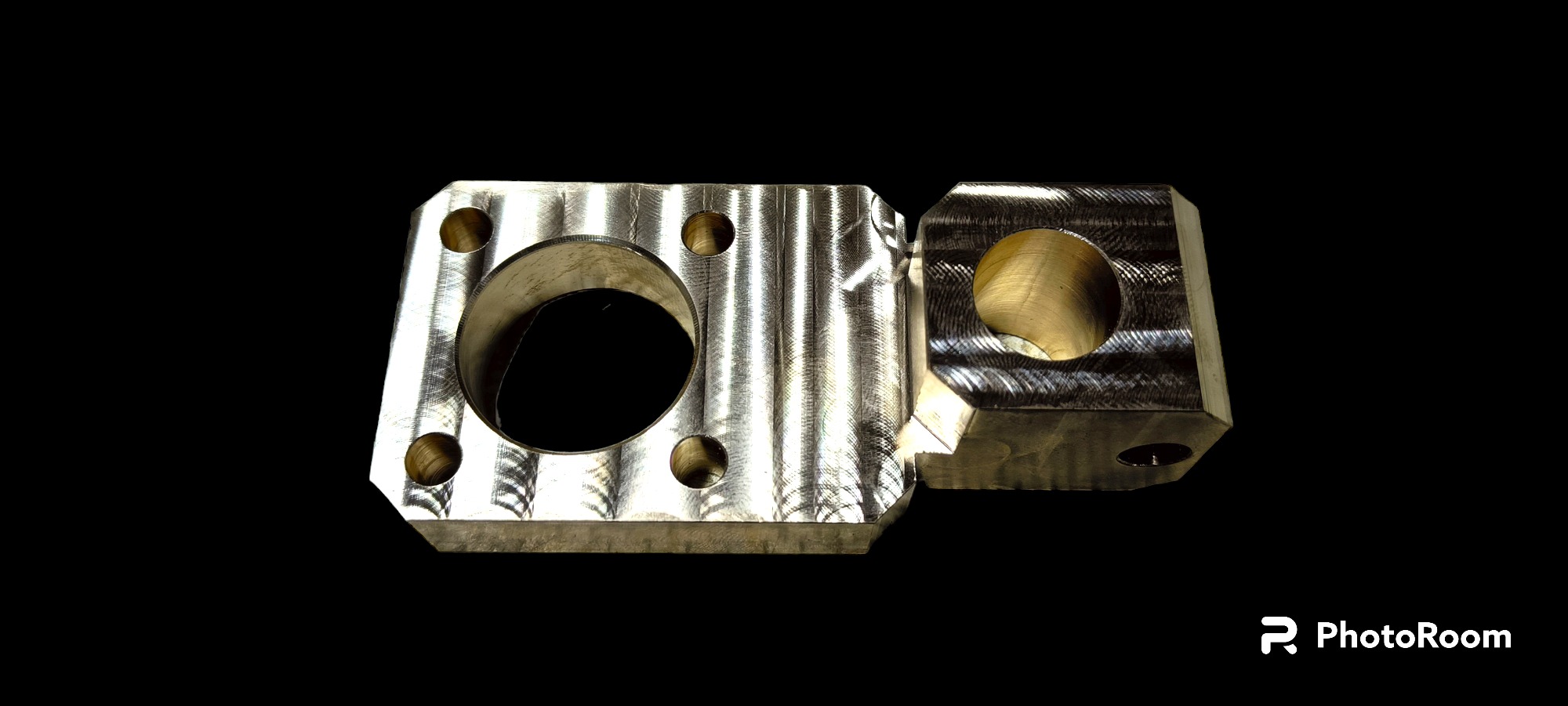 Dwa metalowe elementy z otworami, obrobione skrawaniem, widoczne ślady obróbki, na czarnym tle.