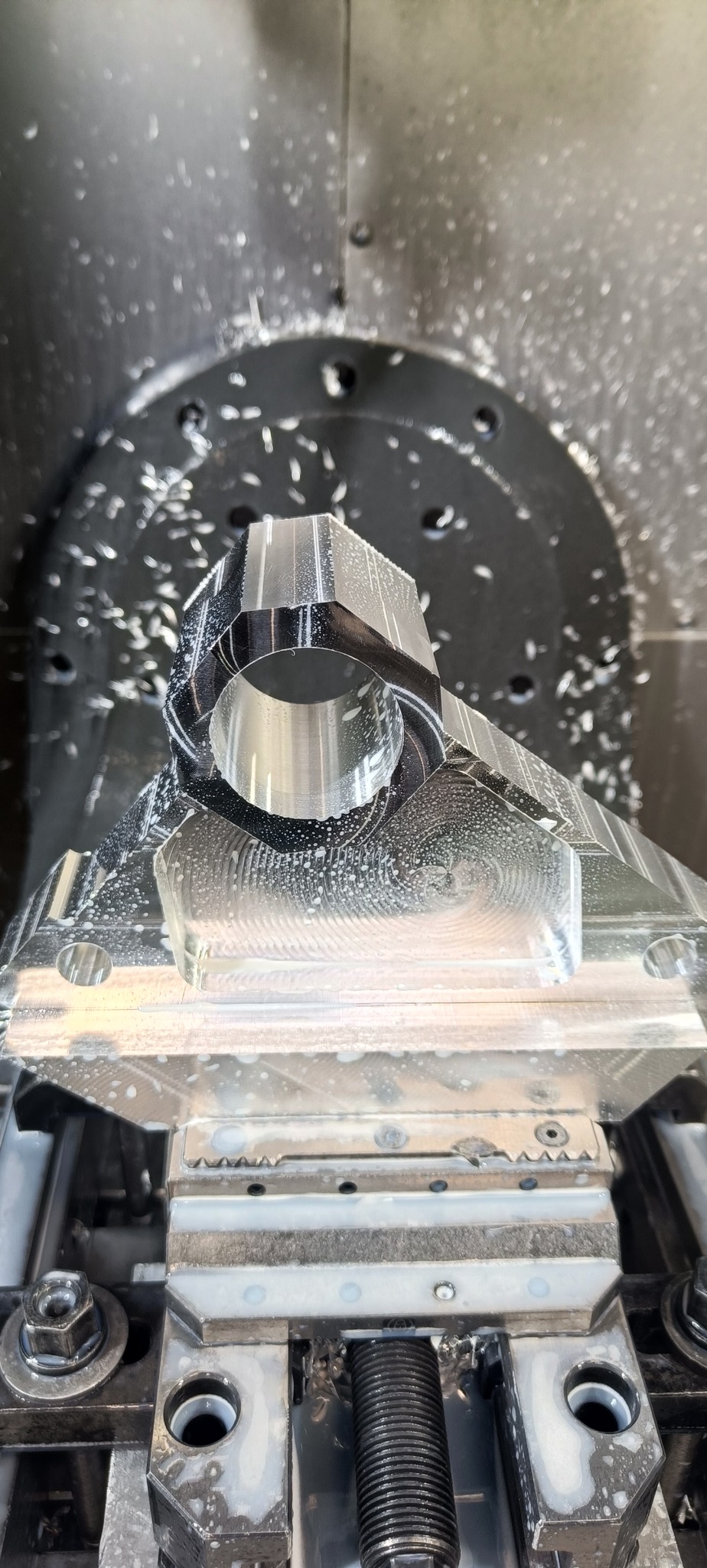 Metalowy element w trakcie obróbki na frezarce CNC, widoczne wióry i chłodziwo.