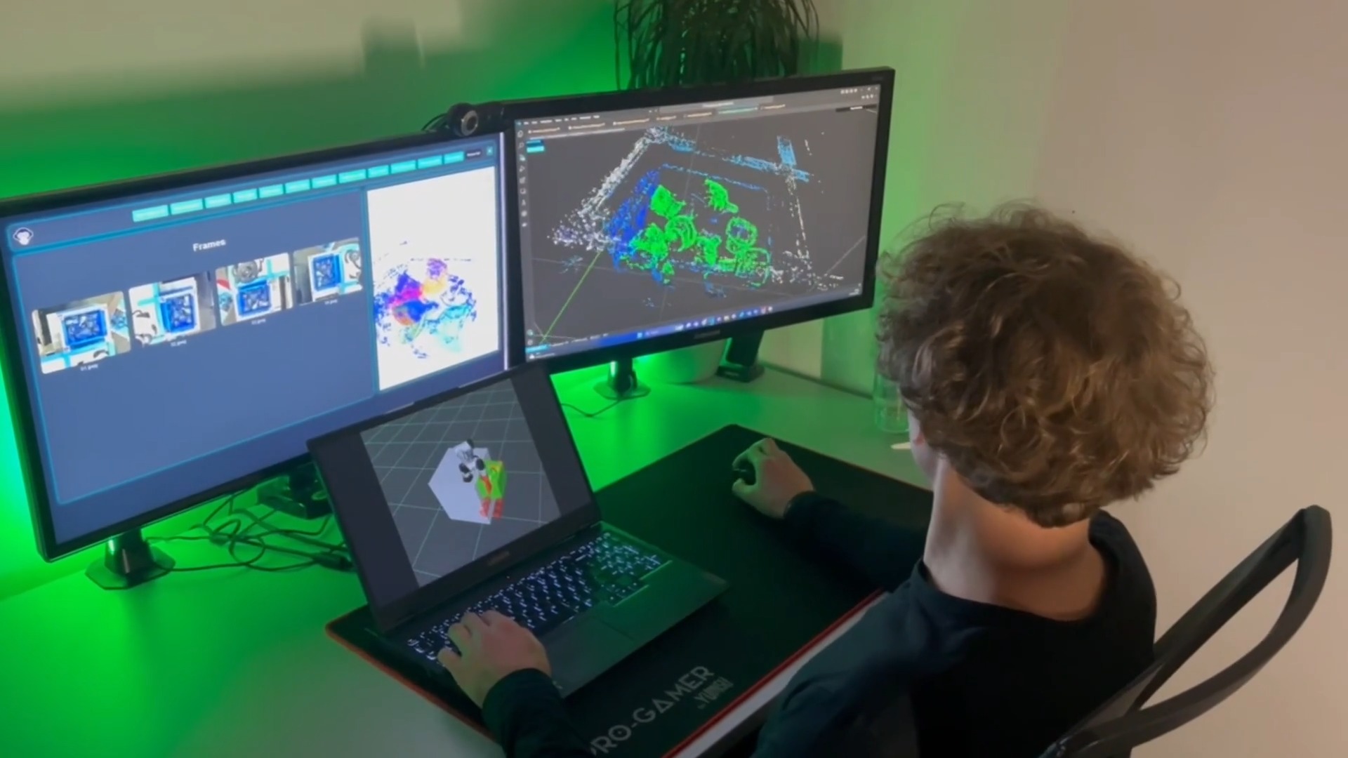 Mężczyzna siedzi przed biurkiem z dwoma monitorami i laptopem, na ekranach widoczne modele 3D i interfejs programu do modelowania, podświetlenie LED za monitorami tworzy zieloną poświatę.