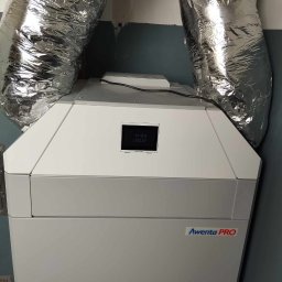 MAR-TECH Zagozda - Szara jednostka rekuperacji Awenta PRO z podłączonymi, srebrnymi, elastycznymi przewodami wentylacyjnymi w Poddębicach.