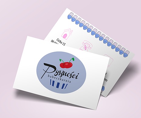Dwie wizytówki z logo i danymi kontaktowymi piekarni, na jednej w tle rząd babeczek z oczami i uśmiechem.