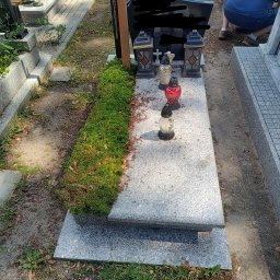 Patrycja Langa - Granitowy nagrobek z mchem, lampionami i zniczami, widok z góry.