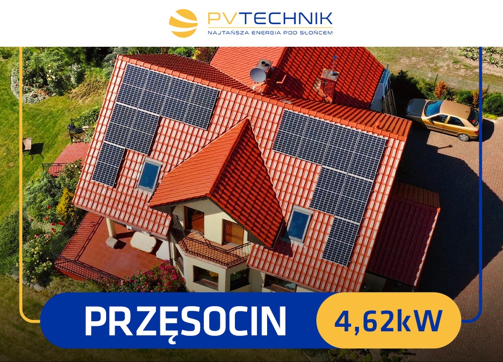 Widok z lotu ptaka na dom z czerwoną dachówką i zainstalowanymi panelami słonecznymi. Na dachu widoczna antena satelitarna. Obok domu stoi zaparkowany samochód.