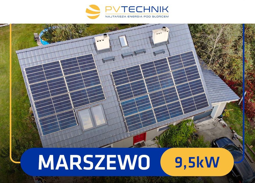 Widok z góry na dom z szarą dachówką, na której zamontowano panele słoneczne; widoczne dwa kominy, okno dachowe, czerwone drzwi wejściowe, fragment ogrodu i zaparkowany samochód.