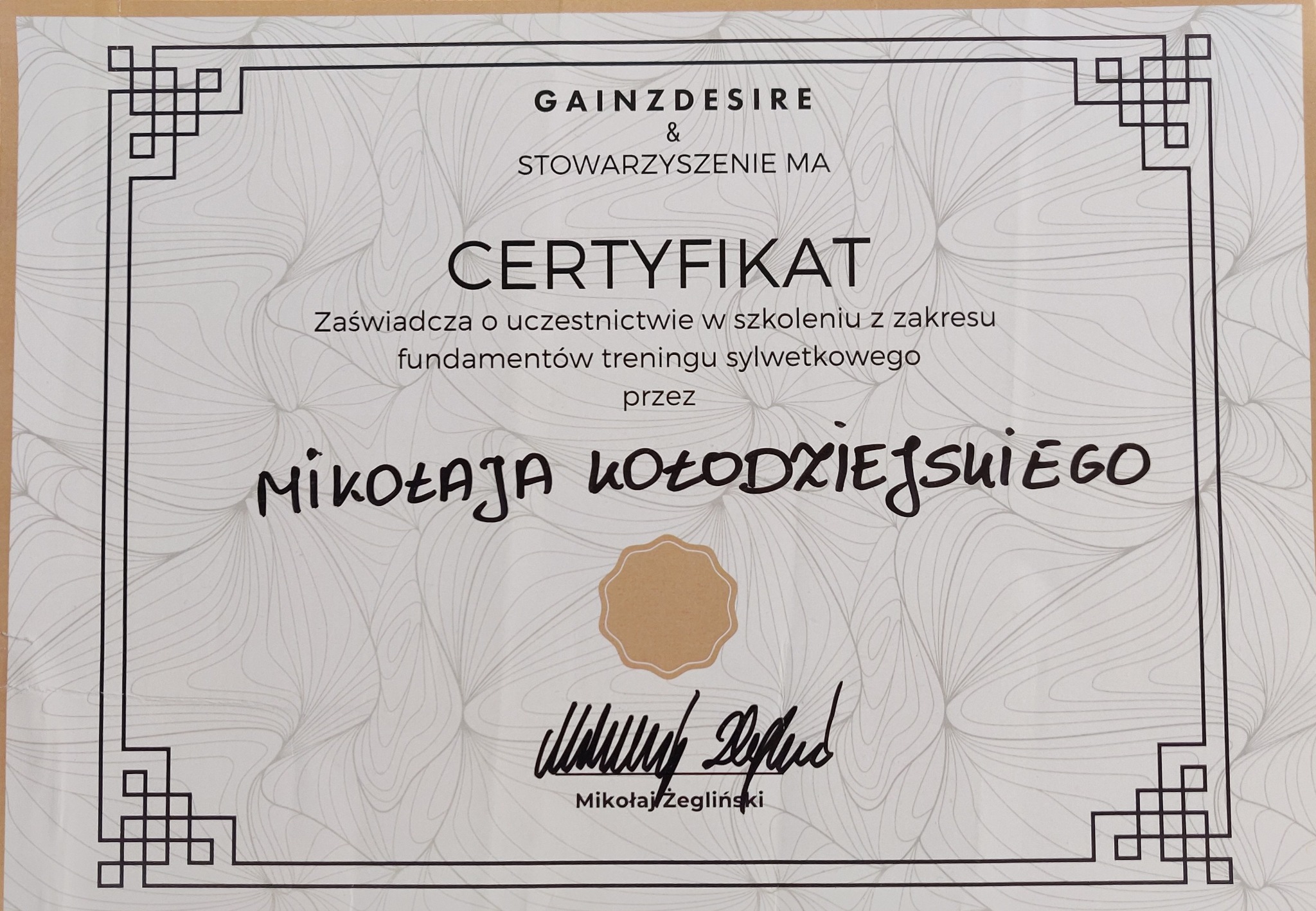 Certyfikat ukończenia szkolenia z zakresu fundamentów treningu sylwetkowego sygnowany przez GainzDesire & Stowarzyszenie MA, podpisany przez Mikołaja Żeglińskiego.