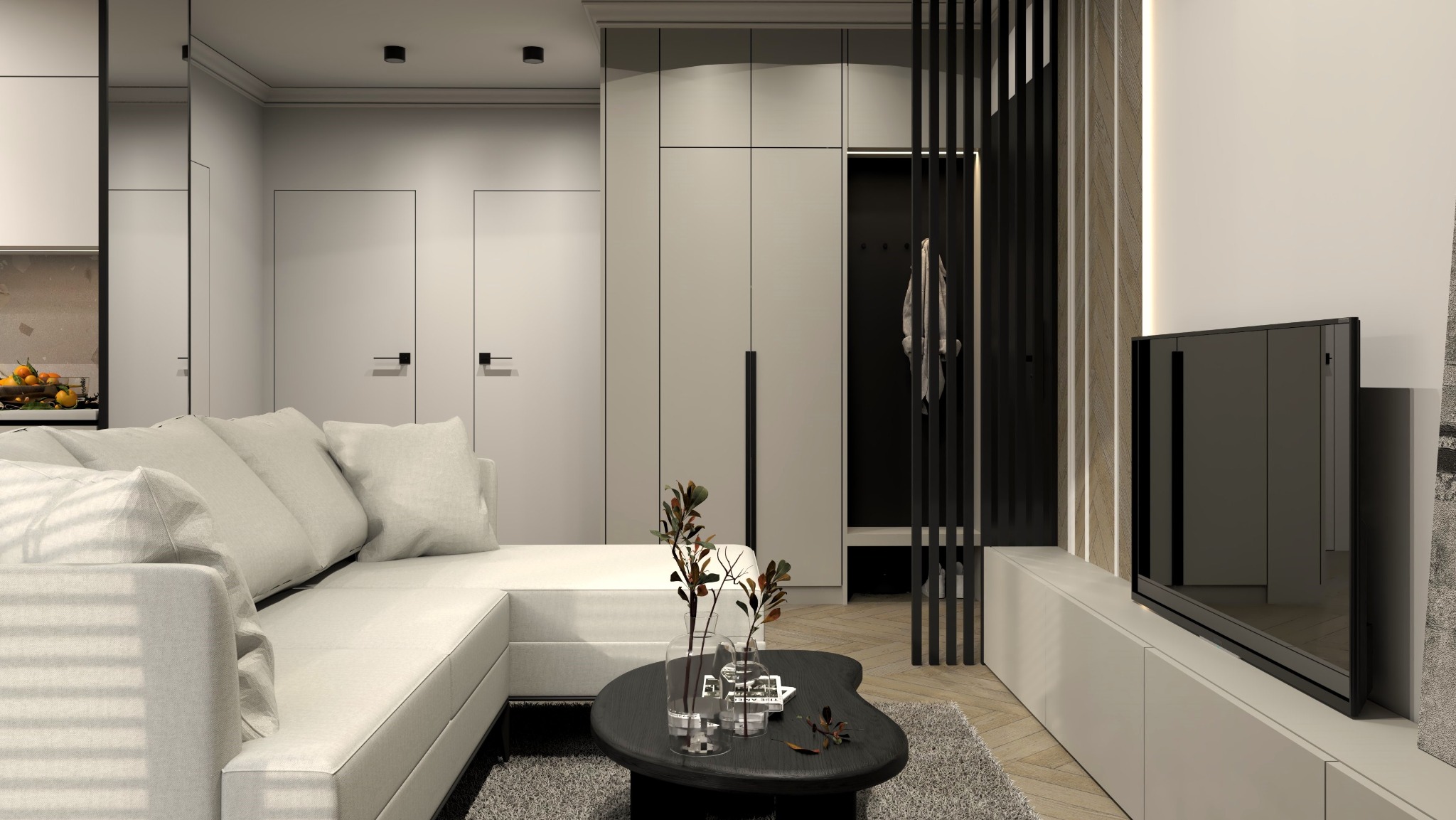 Nowoczesny salon w odcieniach szarości i bieli z narożną sofą, czarnym stolikiem kawowym z dekoracyjnymi wazonami i roślinami, oraz zabudową meblową z szafami i telewizorem na ścianie.
