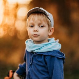 Weronika Zelewska Fotografia-Usługi Fotograficzne - Portret małego chłopca w czapce kaszkietówce i niebieskiej bluzie z kapturem, na tle rozmytych, złotych świateł.