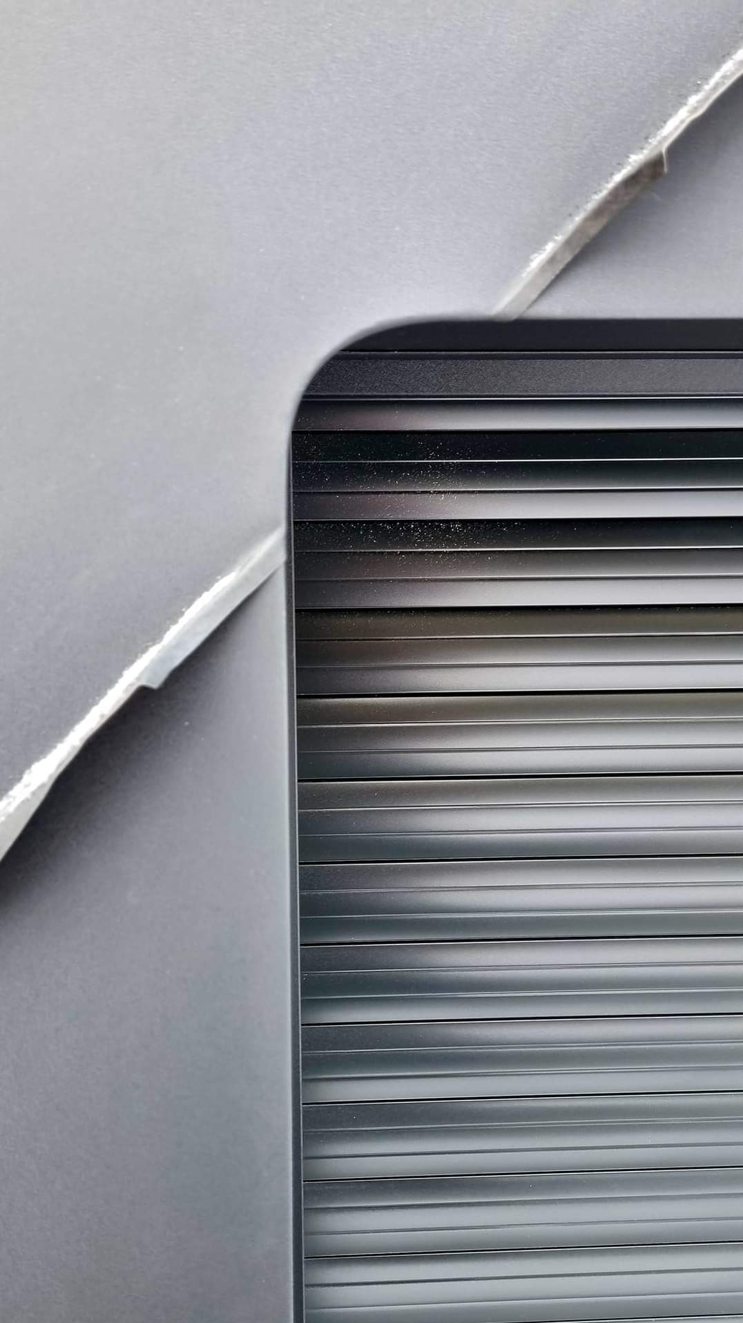 Szczegółowe ujęcie fragmentu obróbki blacharskiej, widoczne poziome listwy w kolorze grafitowym i krawędź blachy z minimalnymi śladami zabrudzeń.
