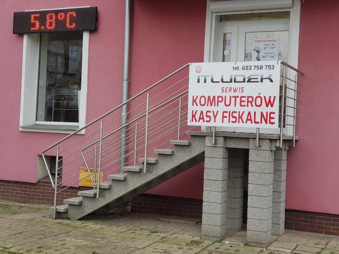 Wejście do serwisu komputerowego ITLUDEK z tablicą informacyjną i schodami. Nad oknem wyświetlacz LED pokazujący temperaturę 5.8°C.