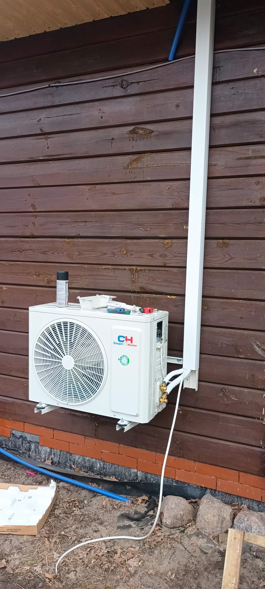 Montaż klimatyzacji Cooper&Hunter na drewnianej elewacji w Szczecinie. Widoczne narzędzia i puszka farby na klimatyzatorze. Instalacja w trakcie podłączania.