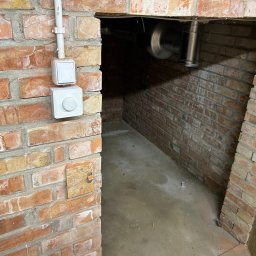 Supply air Bartłomiej Jabłoński - Wnętrze wnęki z cegły z widocznym fragmentem instalacji wentylacyjnej z metalową rurą oraz dwoma białymi przełącznikami na ścianie z cegieł.