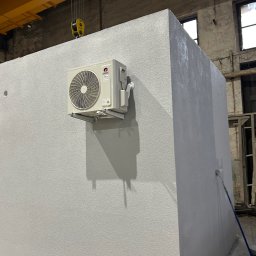 Supply air Bartłomiej Jabłoński - Biały klimatyzator Gree zamontowany na ścianie w surowym wnętrzu przemysłowym, widoczne okna i suwnica. Malowanie ściany w toku.