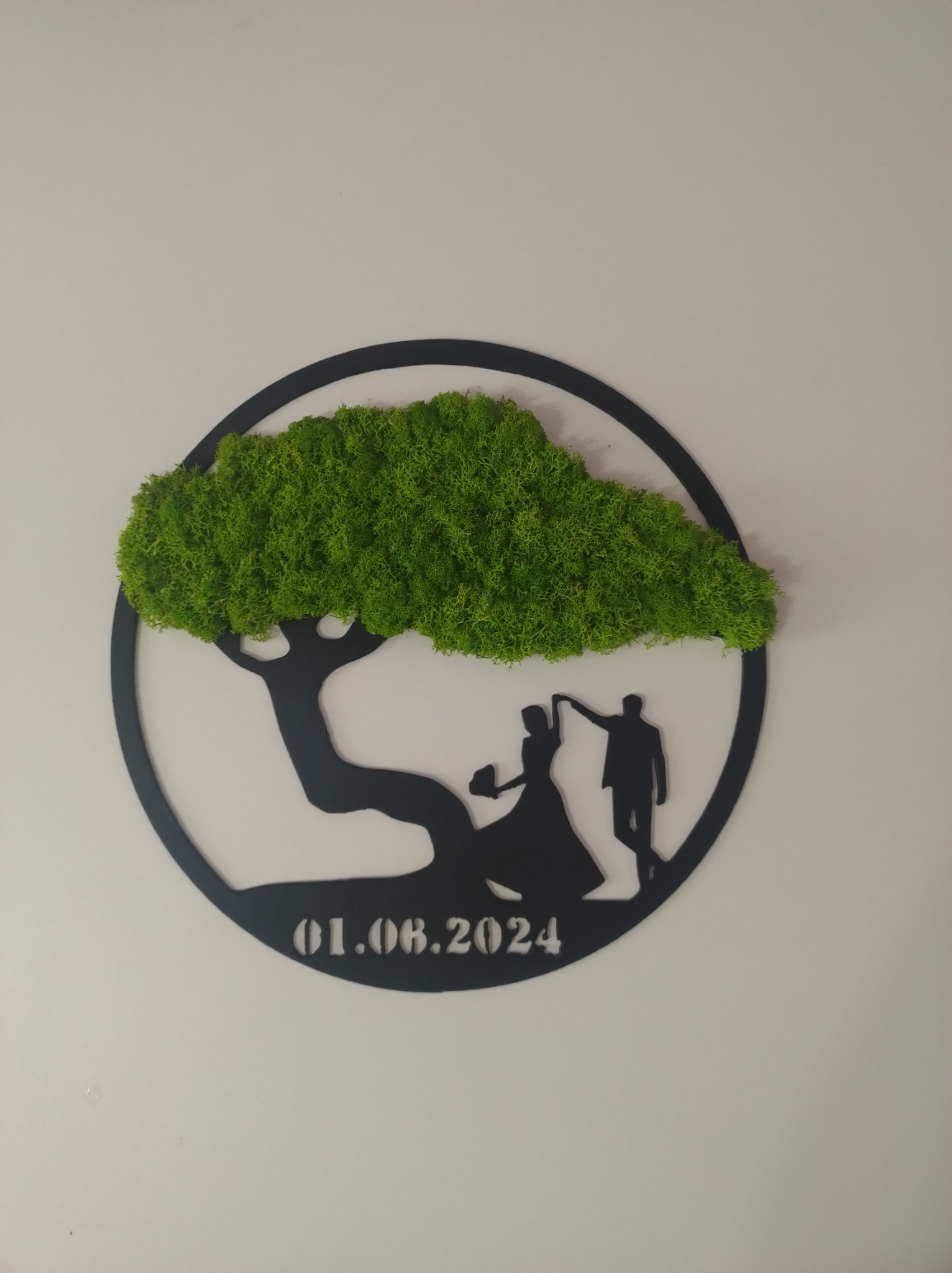 Dekoracja ścienna: czarny, okrągły panel z wyciętym motywem drzewa z koroną z mchu, pod drzewem sylwetki pary tanecznej, poniżej data 01.08.2024.