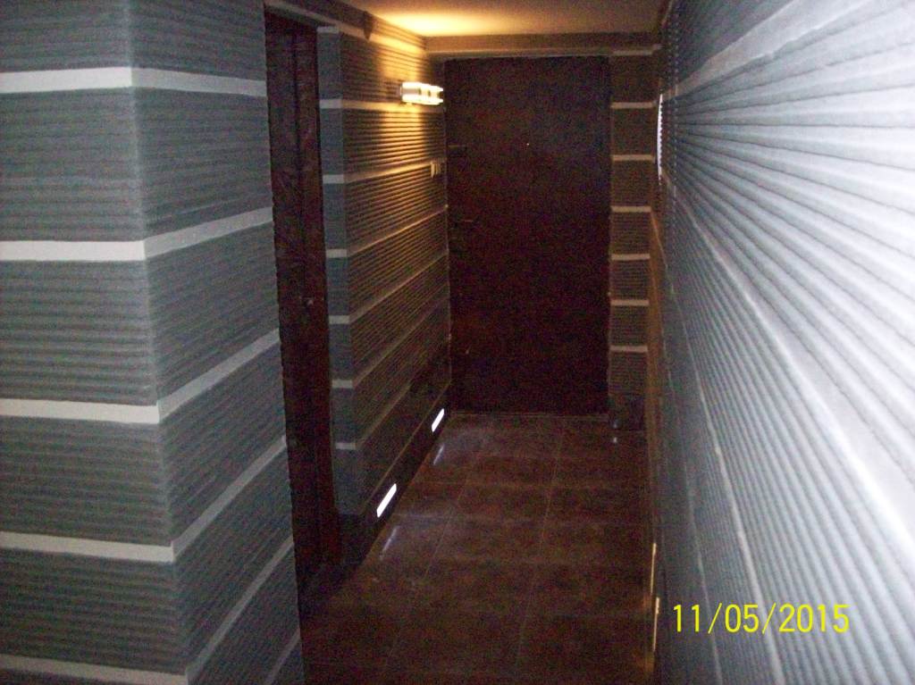 Korytarz po remoncie z szarymi ścianami w poziome pasy z białymi akcentami, ciemnymi drzwiami i brązową podłogą z płytek.