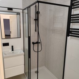 OLEKSANDR SOSKOV - Nowoczesna łazienka z kabiną prysznicową typu walk-in z czarnymi profilami, białą umywalką nablatową i szarymi płytkami imitującymi kamień.