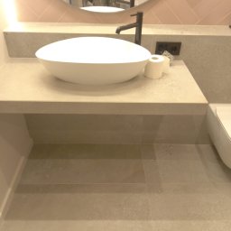 Sur-Bud - Nowoczesna łazienka z okrągłą umywalką nablatową, czarną armaturą i jasnoróżowymi płytkami ułożonymi w jodełkę nad blatem, widoczne odbicie osoby w lustrze.