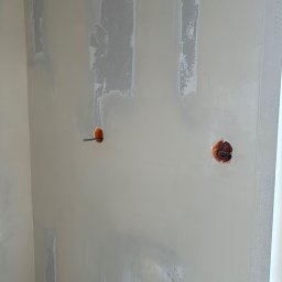 Tomek - Ściana po szpachlowaniu z widocznymi puszkami elektrycznymi. Wyrównana powierzchnia gotowa pod malowanie. Widoczne ślady po łataniu i szpachlowaniu.