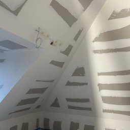 Tomek - Skośne poddasze po szpachlowaniu, przygotowane do malowania. Widoczne łączenia płyt gipsowo-kartonowych i instalacja elektryczna.