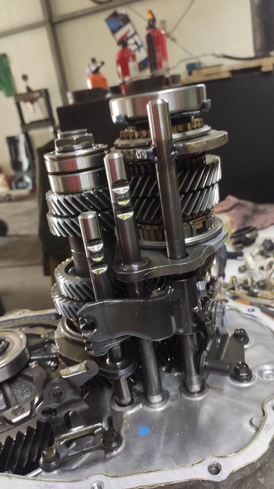 Wnętrze skrzyni biegów samochodowej z widocznymi kołami zębatymi i wałkami, podczas naprawy w warsztacie.