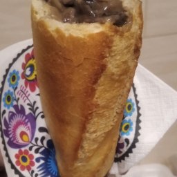 POLSKIE STOWARZYSZENIE RODAK - Baguette faszerowana grzybami, podawana na serwetce z ludowym wzorem kwiatowym.