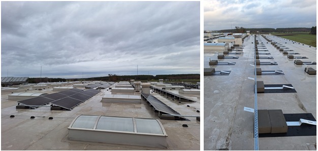 Montaż paneli fotowoltaicznych na płaskim dachu przemysłowym z widocznymi świetlikami i elementami mocującymi, pochmurne niebo w tle.