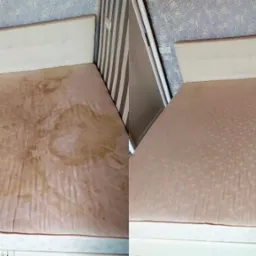 Materac z widocznymi plamami przed i po czyszczeniu, ujęcie z góry, widoczne różnice w kolorze i czystości tkaniny, tło stanowią ściany w paski i z wzorem roślinnym.