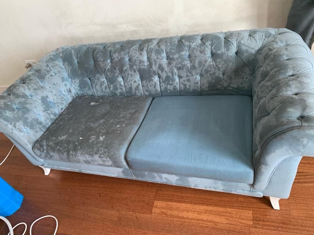 Turkusowa sofa Chesterfield z wyraźną różnicą w czystości między wypraną a niewypraną częścią siedziska, ukazująca skuteczność zabiegu.