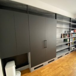 HS MEBLE Hubert Słowikowski - Czarna szafa na wymiar z półkami na książki, szare wykończenie, drewniana podłoga. Minimalistyczny design, nowoczesne wnętrze.