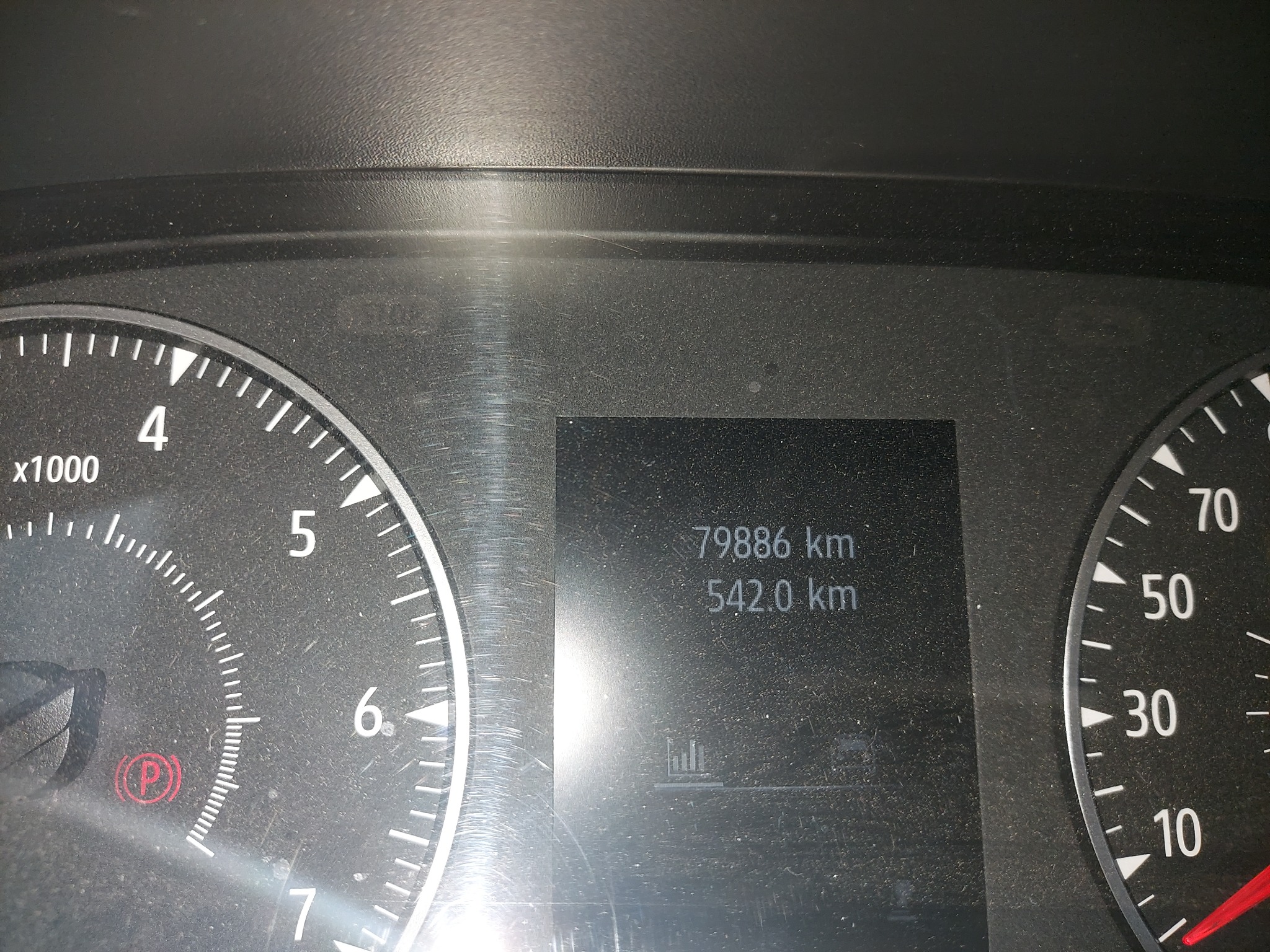 Częściowy widok deski rozdzielczej samochodu z widocznym licznikiem kilometrów, wskazującym przebieg 79886 km i dystans 542 km.