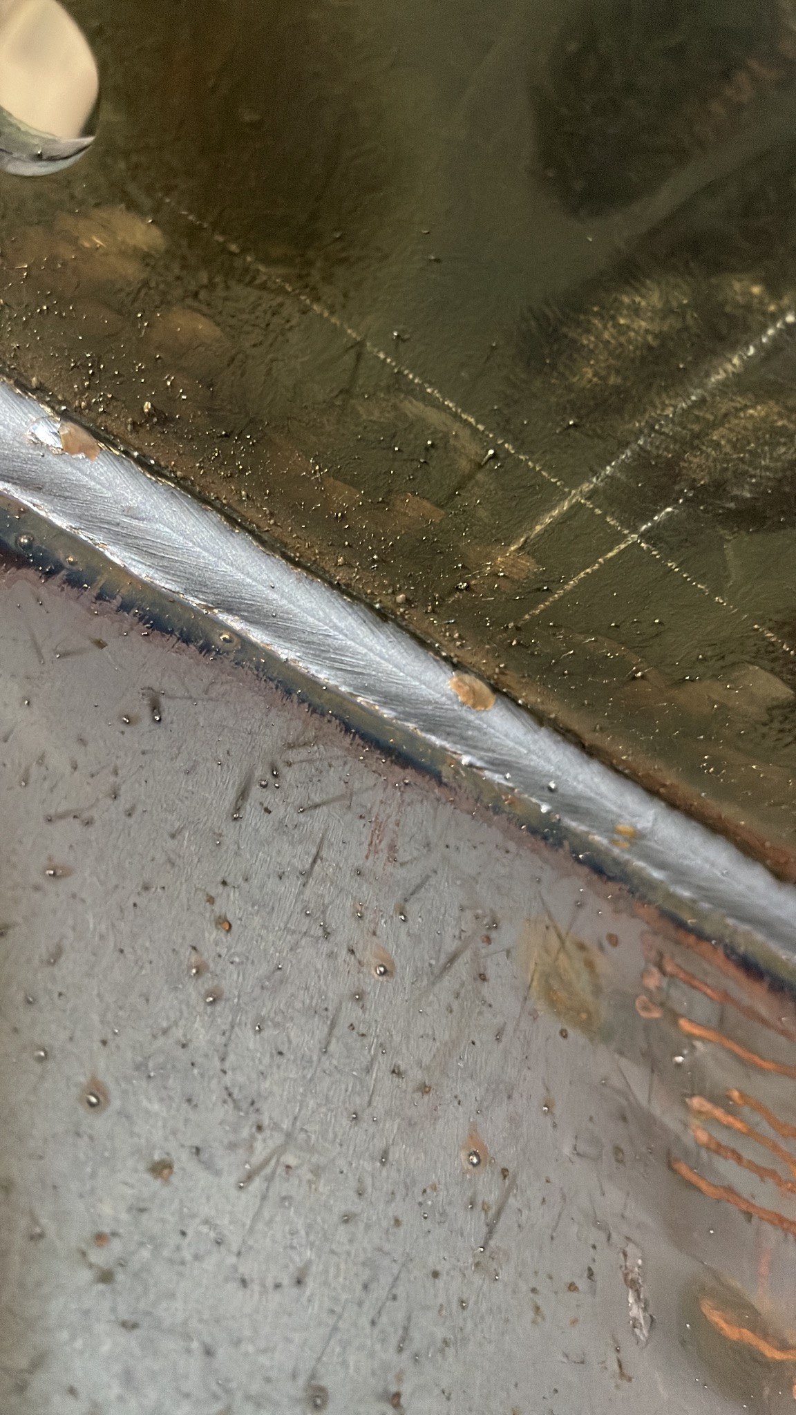 Zbliżenie na spoinę łączącą dwie metalowe powierzchnie, widoczne drobne niedoskonałości i ślady po obróbce.