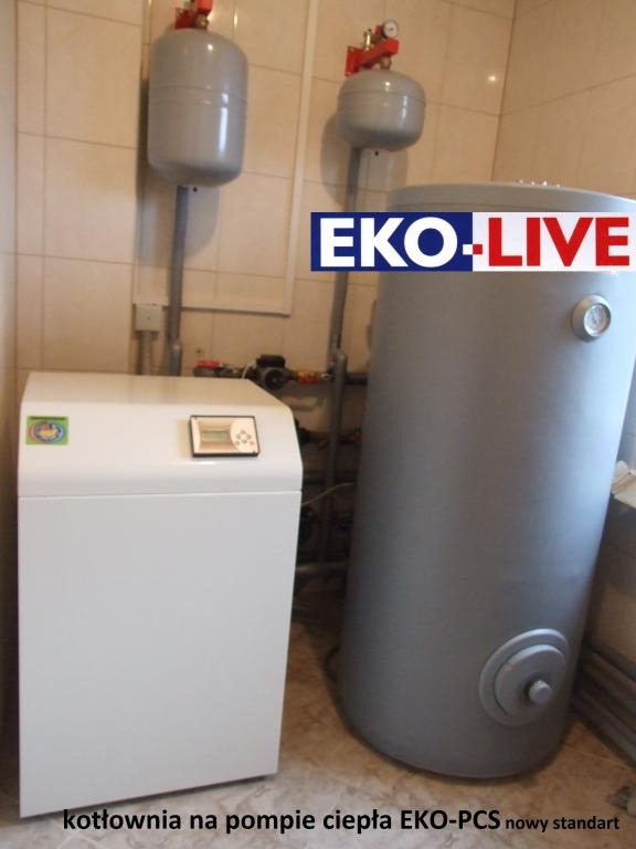 Kompaktowa kotłownia z pompą ciepła EKO-PCS w pomieszczeniu z ceramiczną okładziną ścienną, widoczne zbiorniki wyrównawcze i zasobnik ciepłej wody z logo EKO-LIVE.