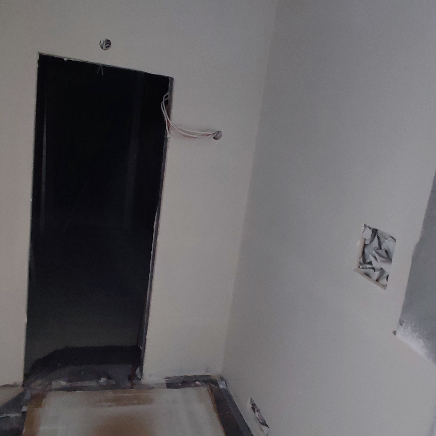 Przygotowanie ściany do malowania: widoczne przewody elektryczne wystające ze ściany, otwór po gniazdku zabezpieczony folią, przygotowane futryny drzwiowe.