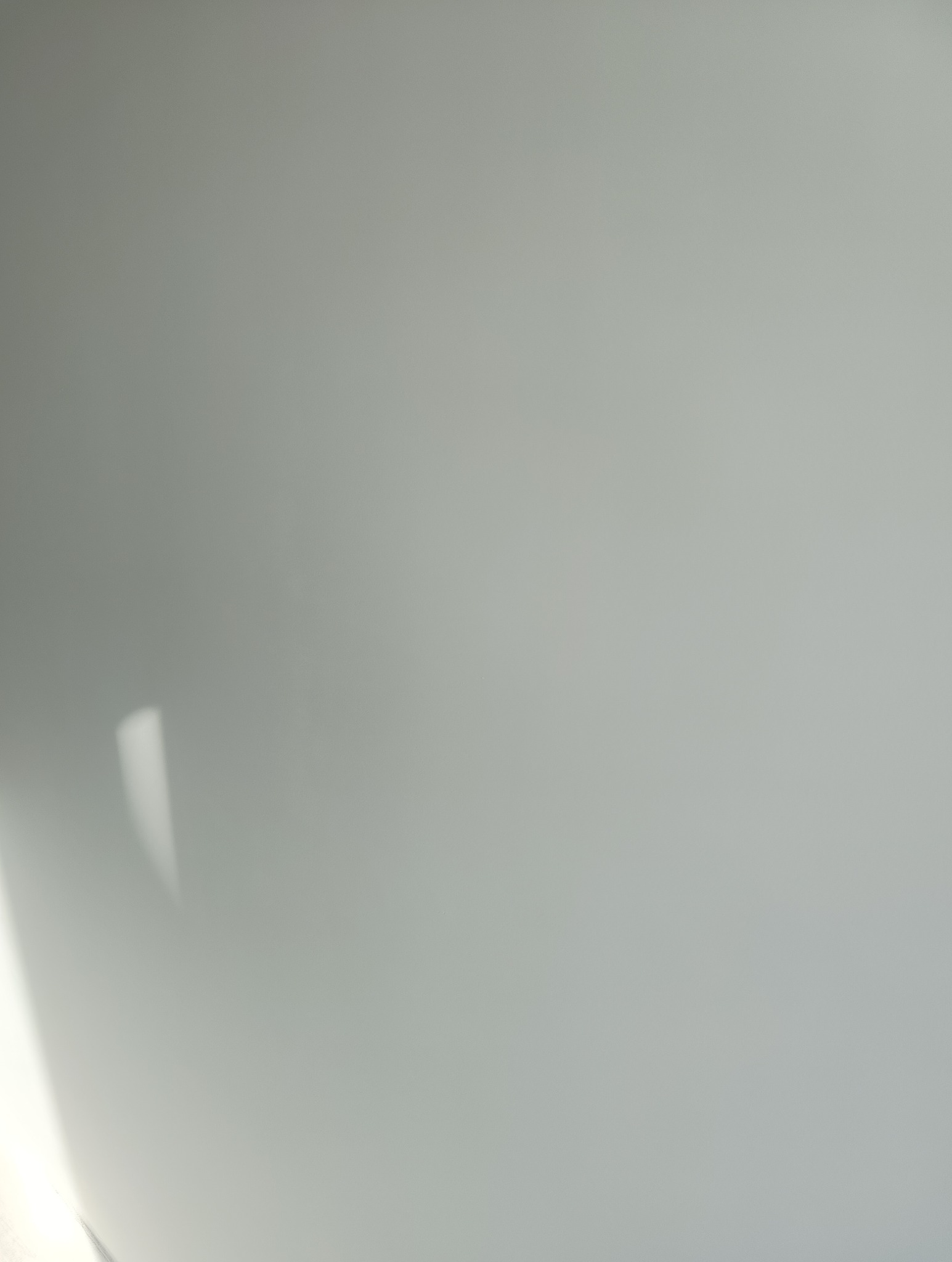 Światło słoneczne padające na gładką, szarą ścianę wewnętrzną, tworząc delikatny gradient i refleksy.