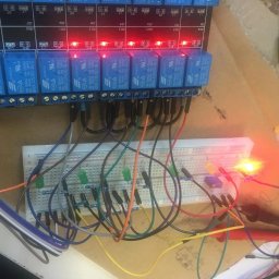 AWG SPÓŁKA Z OGRANICZONĄ ODPOWIEDZIALNOŚCIĄ - Testowanie obwodu elektrycznego z użyciem płytki stykowej, modułu przekaźników z diodami LED sygnalizującymi stan oraz multimetru z czerwoną sondą, widoczne liczne przewody połączeniowe.